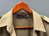 un trench-coat suspendu à un cintre accroché au mur, sur fond bleu
