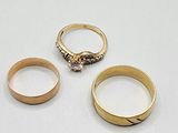 three gold rings and a diamond ring on a white surface