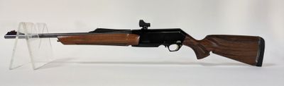 le fusil est posé sur un support transparent, sur une surface blanche