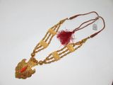 un collier en or orné de perles rouges et d'une plume rouge