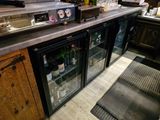 un bar avec une porte vitrée et un comptoir sur lequel sont disposées des bouteilles de vin