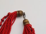 red beaded tassels with gold accents on a white background