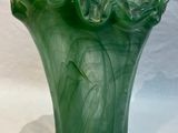 un vase vert posé sur une surface blanche