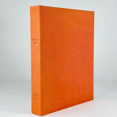 an orange book sitting on top of a white table next to a white wall