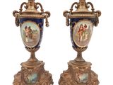 une paire de vases anciens posés sur des socles, sur une surface blanche