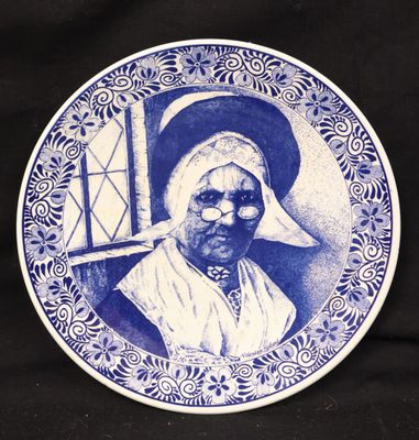 a blue and white plate with a picture of an old woman on it