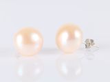 pair of pink pearl earrings on white background with reflection