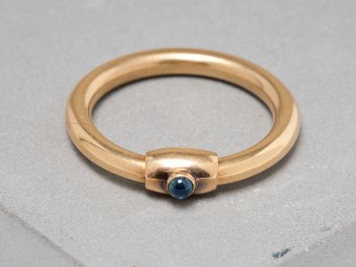 gros plan d'une bague en or avec une pierre bleue