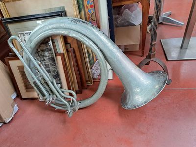a silver trumpet sitting on the floor next to a pile of framed pictures