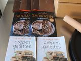 two cookbooks on a table with a plate of food