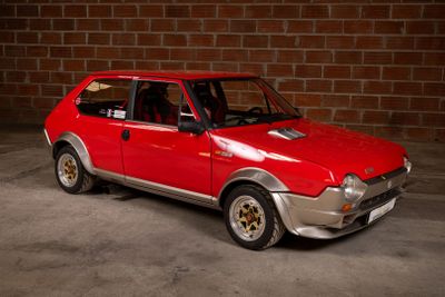 a red car that is parked in front of a brick wall
