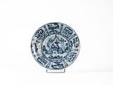 une assiette bleue et blanche posée sur un support sur une surface blanche