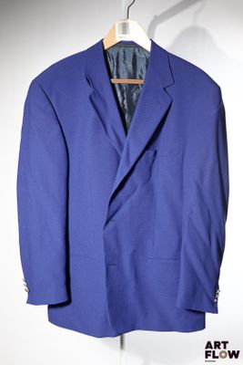 un costume bleu suspendu à un cintre sur un mur blanc