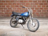 a blue motorcycle parked in front of a brick wall