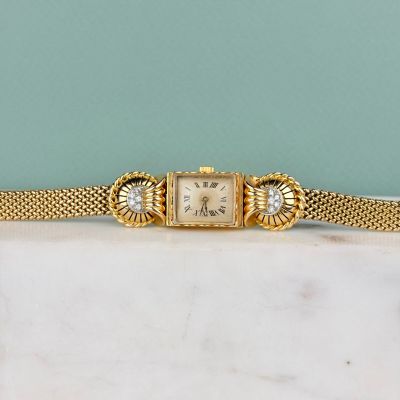 une montre de femme ancienne avec un bracelet en mailles d'or