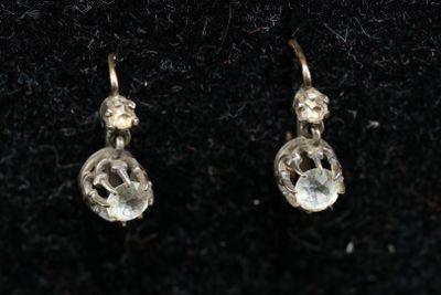 une paire de boucles d'oreilles en or ornées de cristaux transparents sur un fond noir