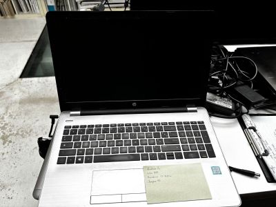 un ordinateur portable posé sur un bureau, à côté d'un stylo et d'une feuille de papier