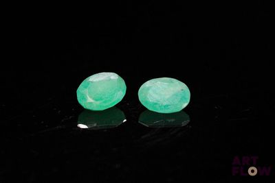 two pieces of green jade are sitting on a black surface