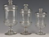 Trois bocaux en verre transparent munis de couvercles sont posés sur une table