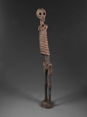 une statue en bois représentant un squelette au long cou et aux longs bras