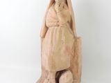 statue of a woman sitting on a rock with her hands on her knees