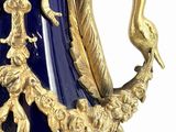 a blue vase with a gold handle and a bird on it