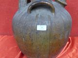 un vase marron muni d'une étiquette, posé sur un tissu rouge