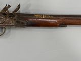 un vieux pistolet avec une poignée en bois sur une surface blanche