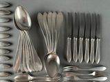 a lot of silver spoons and forks laid out on a table