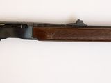 un fusil accroché au mur d'une pièce aux murs blancs