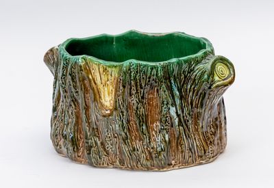 un vase vert et marron orné d'un motif représentant une souche d'arbre