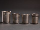 four silver shot glasses sitting next to each other on top of a table