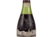 une vieille bouteille de vin posée sur une surface blanche
