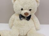 a white teddy bear with a bow tie sitting on a table