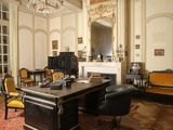 a room with a desk, chairs, and a fireplace