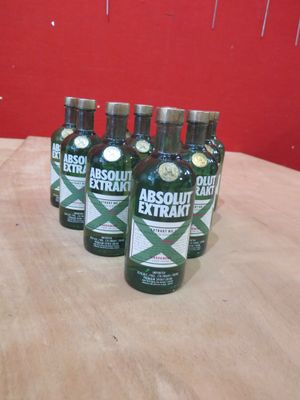 Six bouteilles d'Absolut Extra sont posées sur une table devant un mur rouge.