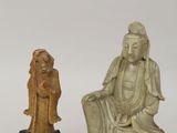 deux figurines sculptées représentant une femme et un homme assis sur un rocher