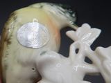une figurine représentant un oiseau tenant une pièce dans le bec