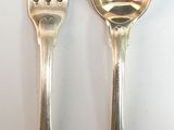 two silver spoons and a fork on a table