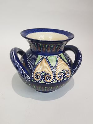 un vase bleu orné d'un motif, posé sur une table