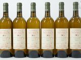 six bouteilles de vin sont alignées sur une surface blanche