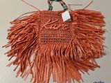 un sac à main orange dont la poignée est ornée de franges