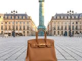 brown leather handbag sitting on the ground in front of a tall building