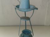 a blue watering pot sitting on a stand on a table