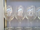 Plusieurs verres à vin vides sont alignés sur une étagère en verre