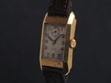 an image of a gold plated wrist watch on a black background