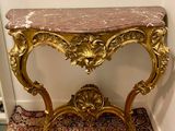 une petite table avec un plateau en marbre posée sur un tapis rouge