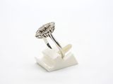 a close up of a diamond ring on a stand on a white surface