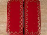 two red boxes with gold designs on them sitting on a wooden table
