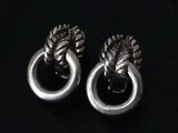 a pair of silver earrings with a knot on each end
